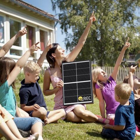 A group of children with a REC solar panel